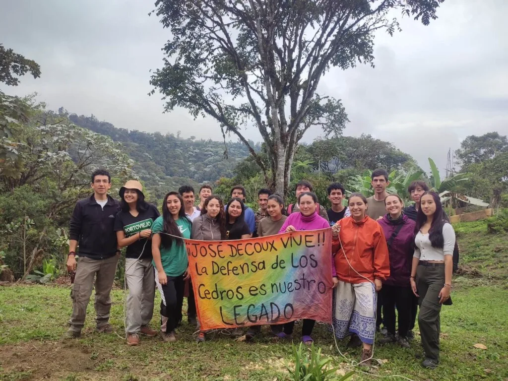 Pontifical Catholic University of Ecuador students at Los Cedros with Scientific Station staff holding banner describing the cloud forest as Josef DeCoux's legacy