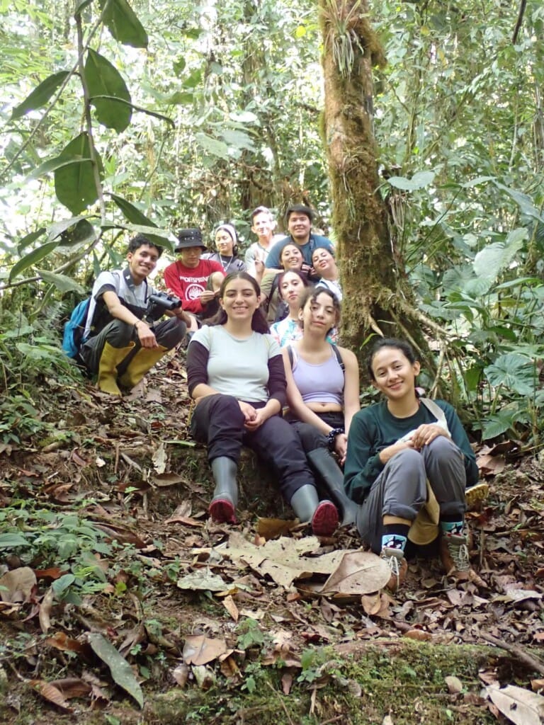 Pontifical Catholic University of Ecuador students together sitting on trail within Los Cedros cloud forest