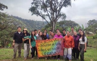 Pontifical Catholic University of Ecuador students at Los Cedros with Scientific Station staff holding banner describing the cloud forest as Josef DeCoux's legacy